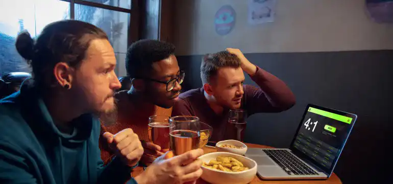 três amigos tomando cerveja e olhando para a tela do computador 